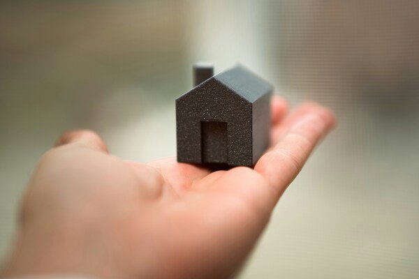 A close-up photo of a miniature house placed on an open palm