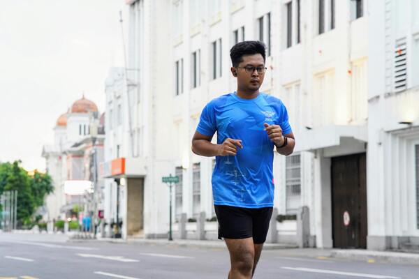 A man in blue shirt jogging in the street