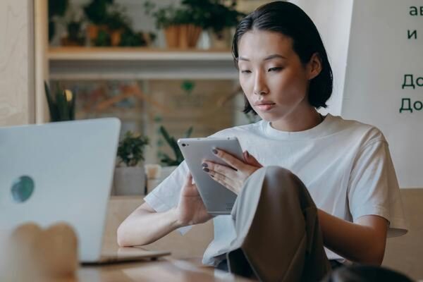 Young woman using a tablet and laptop to research investments before deciding whether to work with a financial advisor.