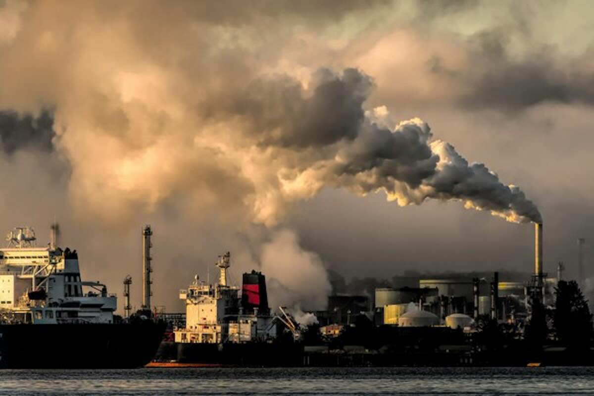 Industrial smokestacks releasing emissions, highlighting the importance of low carbon investing and climate-conscious portfolios.