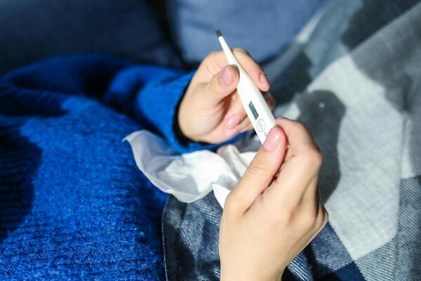 A person holding a body thermometer