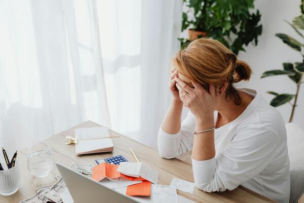 A woman with her hands on her head while looking at the receipts on her table