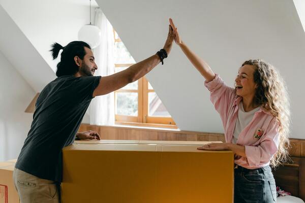 Two people joined hands together with packed cardboard boxes for moving houses