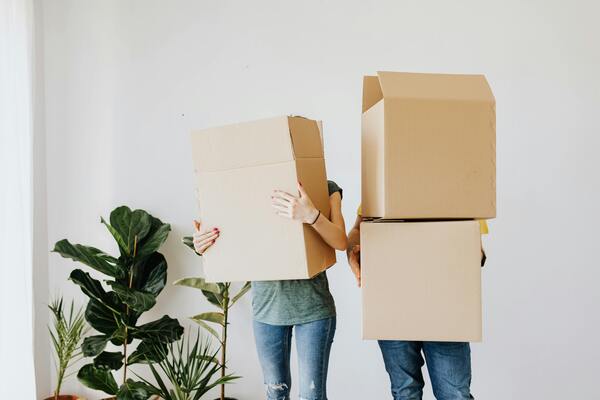 Two people carrying cardboard boxes in their faces