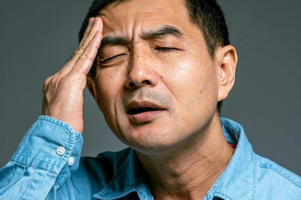 A middle-aged man with his hand on his temple as a sign of headache