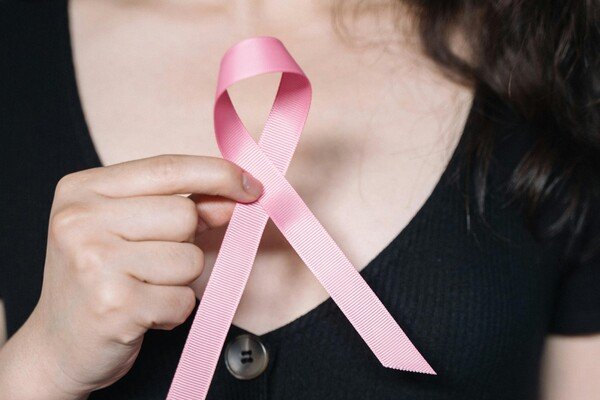 A woman holding a small pink ribbon
