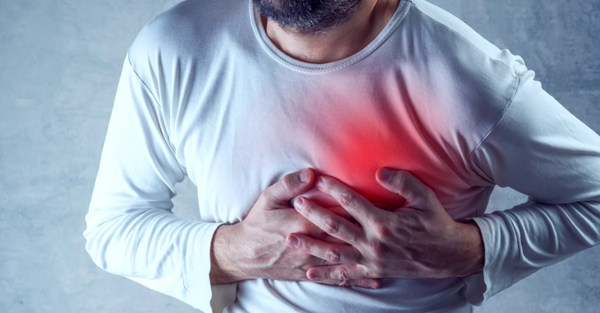 A person with his hands on his chest as a sign of getting a heart attack