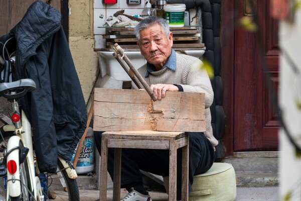 Elderly man woodworking with hand tools in a small workshop, representing senior workers, craftsmanship, and lifelong skills.