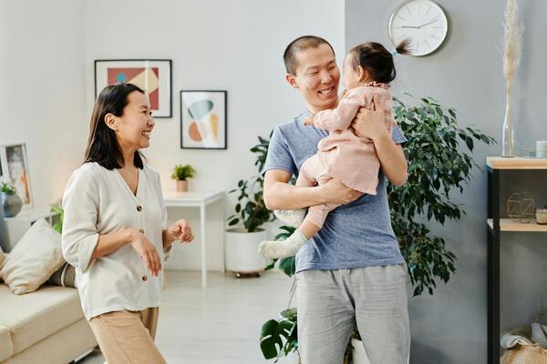 Happy parents holding their baby in a bright living room, representing family life, parenthood, and household financial planning.