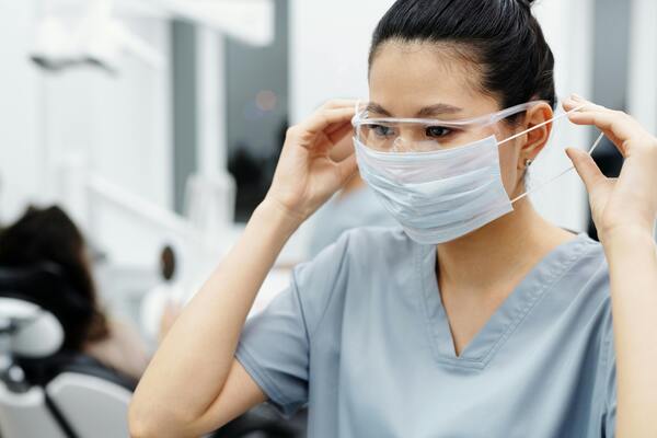 Nurse wearing protective mask and scrubs preparing for patient care in a modern hospital environment