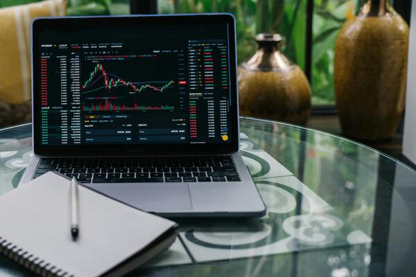 Laptop displaying stock market charts and trading data on a desk, representing investment analysis, market volatility, and financial trading.