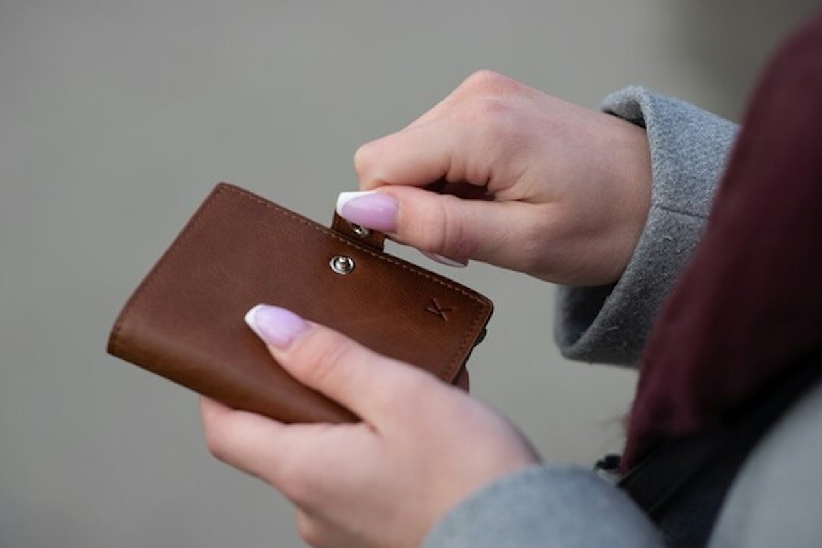 Person opening a wallet after financial fraud, highlighting steps to recover money if hacked or scammed.