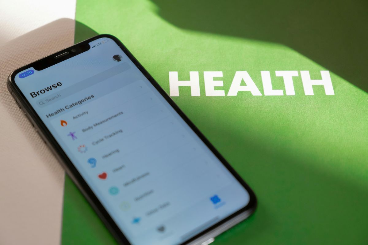 Smartphone displaying health app categories beside bold health text on green background