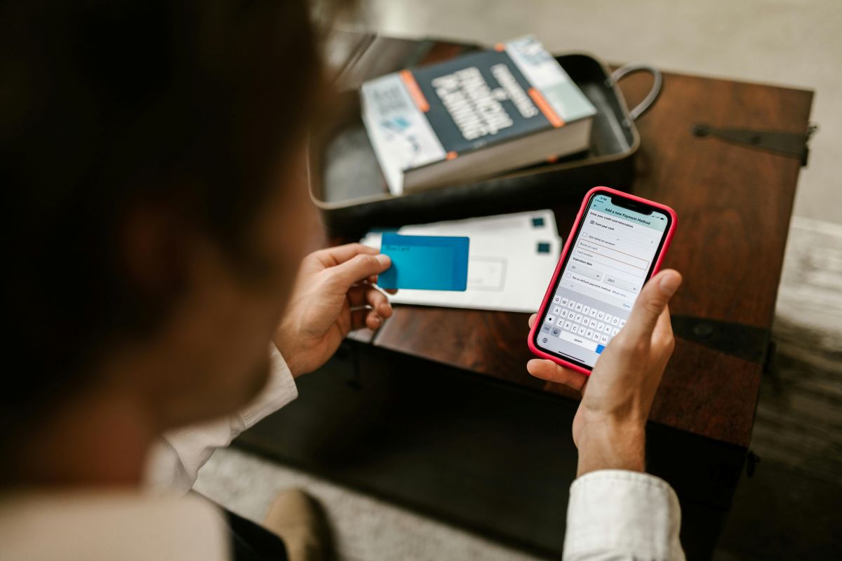 Person making a mobile payment with smartphone and credit card at home