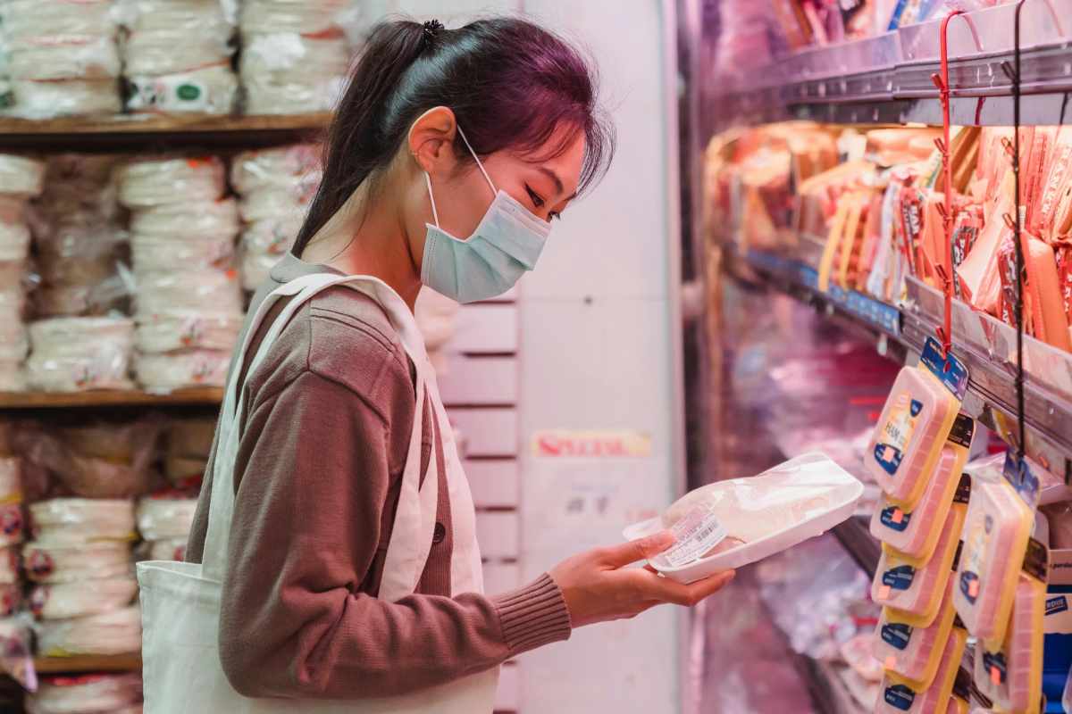 Woman wearing a face mask shopping for packaged food in a grocery store