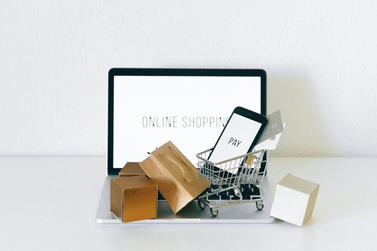 Online shopping setup with laptop, smartphone, credit cards, and mini shopping cart