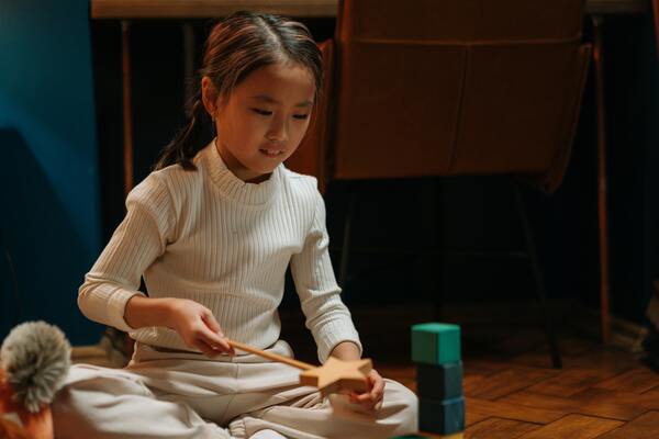 A little girl sits on the floor, happily stacking colorful blocks as she plays.