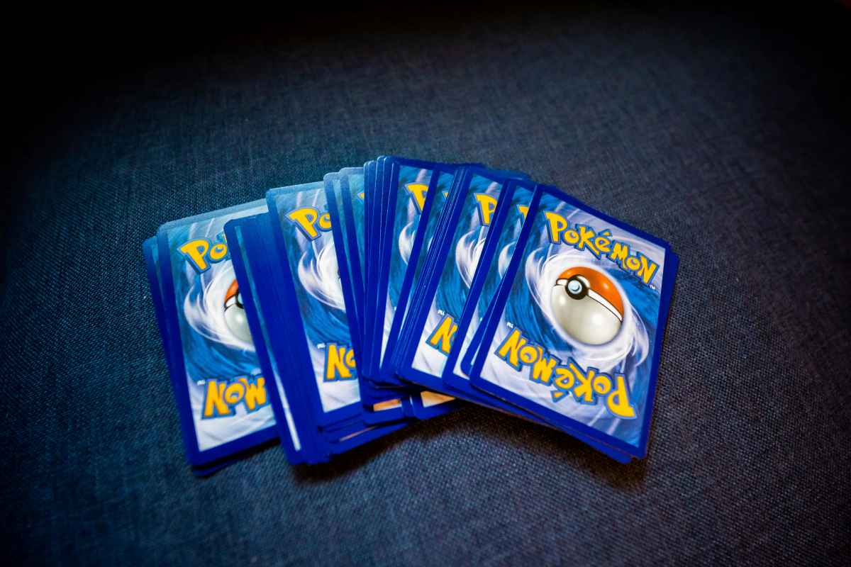 Fan of Pokémon trading cards spread across a dark surface with classic blue Poké Ball card backs visible